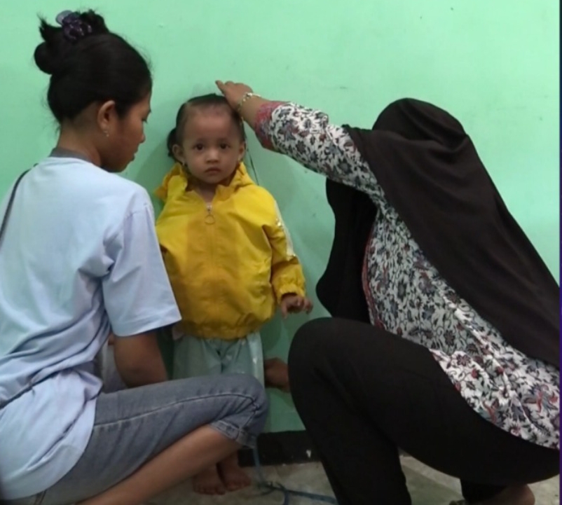 Nala didampingi sang Ibu, Angela sedang mengikuti pengukuran tinggi badan di balai desa Sumberjo Kecamatan Rembang sebelum menerima PMT